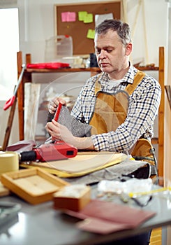 Man upholstering chair in his workshop, measure