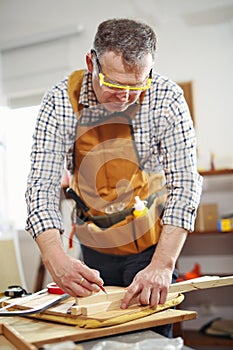 Man upholstering chair in his workshop, measure