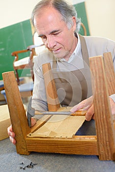 Man upholstering chair in workshop