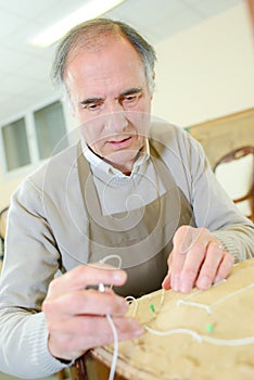 Man upholstering chair in workshop