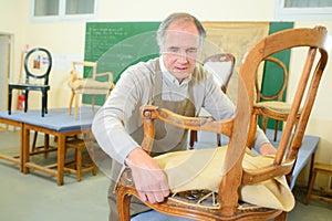 Man upholstering fixing chair in workshop