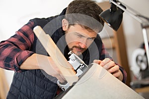 man upholstering round stool seat