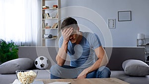 Man upset about defeat of football team, watching tv broadcast, unhappy fan