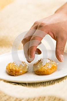 Man use his hand to take a delicious turkish dessert sekerpare with coconut powder