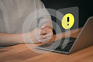Man use a laptop computer with caution warning sign for notification error.