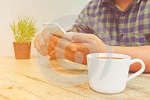 Man use mobile phone and holding coffee cup vintage tone.