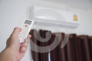 A man use remote controller to set air conditioner temperature in the room.Hand holdind control remote switch of home air