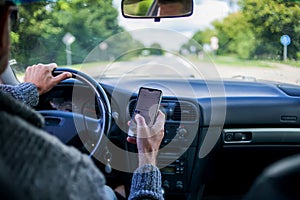 A man use smartphone while driving in the car. Road danger concept