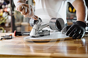 Man use the socket tool or hex keys to remove the nuts on skateboard and adjusts suspension in workshop, Skateboard maintenance