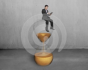 Man use tablet and sit on hourglass