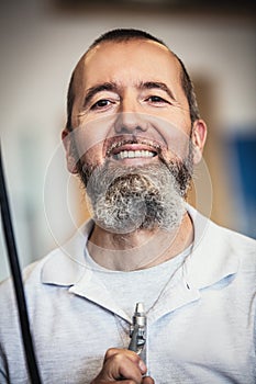 A man uses an air gun to blow his beard up