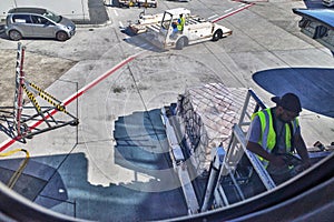 Male airport ground crew loading airplane as seen from passenger inside view