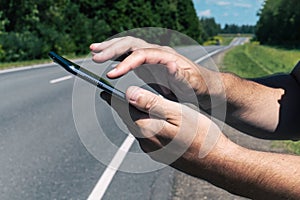 A man uses a digital tablet on a country road