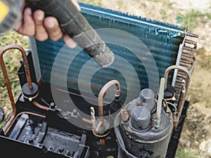 A man uses an electric air blower to dry a cleaned and washed window type air conditioning unit outside. Aircon cleaning service