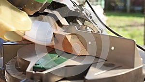 A man uses an electric circular saw to cut wooden bars. Carpenter works on a board outdoors, close-up