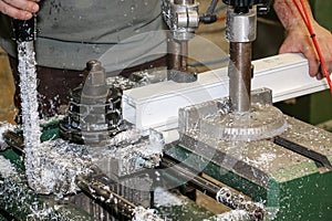 A man uses a machine to adjust a profile in a carpentry specializing in PVC