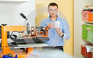 Man uses machine to print on ceramic mug