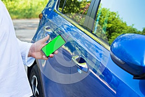 Man uses mobile application on smart phone to lock or unlock car door. Concept of vehicle keyless security