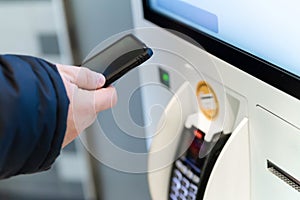 Man uses an nfc payment near a self-service terminal. Paypass, phone contactless payments