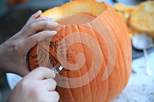 Man uses a paring knife on Halloween pumpkin