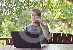 Man uses phone and connected to plug for charge phone battery at home. Man communicates and work by phone technology device