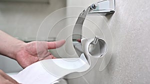 Man uses a roll of toilet paper in the toilet. close up.