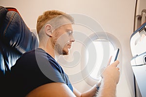 Man uses smart mobile phone in cabin airplane, concept Internet in air stratosphere photo