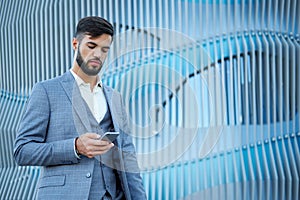 Man uses a smartphone. Businessman urban professional business man using mobile phone. Happy professional wearing suit jacket.