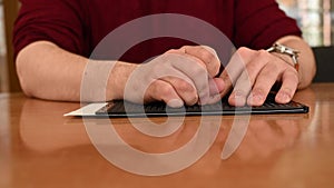 A man uses a special stencil and stylus to write a letter in braille.