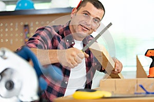 man using abrasive file on length wood