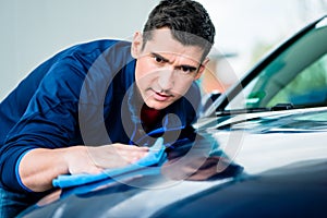 Man using an absorbent towel for drying the surface of a car