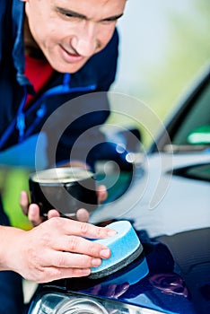 Man using an absorbent towel for drying the surface of a car