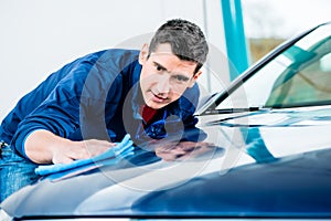 Man using an absorbent towel for drying the surface of a car