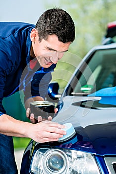 Man using an absorbent towel for drying the surface of a car