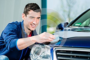 Man using an absorbent towel for drying the surface of a car