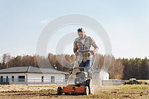 Man using aerator machine to scarification and aeration of lawn or meadow