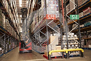 Man using aisle truck in a distribution warehouse, side view