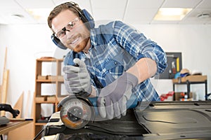 man using angle grinder on car bodywork