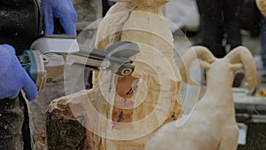 Man using angle grinder with multi cutter saw for carving wooden sculpture