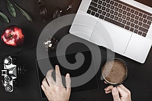 Man using app with digital tablet. Top view of laptop and headphones on a black table