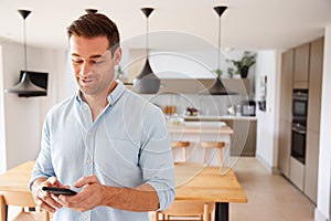 Man Using App On Smart Phone To Control Central Heating Temperature In House