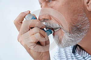 Man using asthma inhaler on white background photo