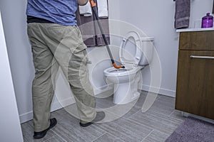 Man using an auger on a toilet