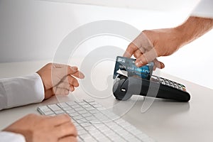 Man using bank terminal for credit card payment at cash department window