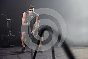 A  Man Using Battle Ropes For Whipping Exercise  in a Gym