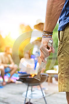 Man using bellows for preparing food in barbecue grill with friends on pier