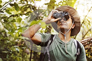 Man using binoculars watching birds in the jungle