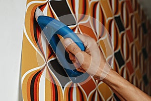 man using a brush to attach wallpaper to a wall