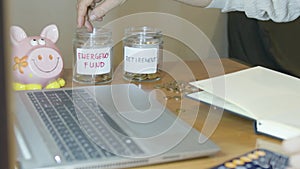 Man using calculator and sorting money into jars for retirement and emergency fund. Budgeting concept