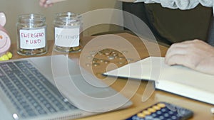 Man using calculator and sorting money into jars for retirement and emergency fund. Budgeting concept